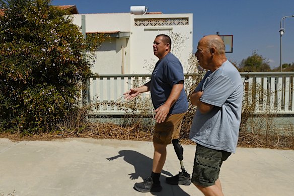 Avida Bahar (left) who lost his right leg after being shot by Hamas walks with a friend to his home in Kibbutz Be’eri.