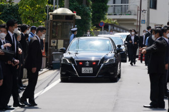 Police officers and security police escort a procession of vehicles which include Japan’s former Prime Minister Shinzo Abe’s body as they arrive at his residence in Tokyo.
