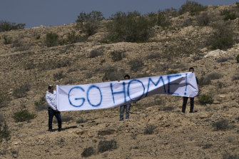 Israeli activists hold a banner against the meeting across from the Kedma hotel where it was taking place, in Kibbutz Sde Boker, Israel.