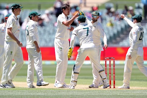 Mitchell Starc is congratulated by teammates after taking the wicket of India’s Wriddhiman Saha.