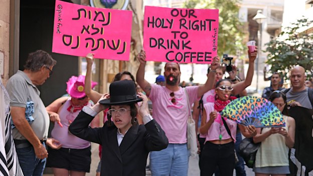 A young ultra-Orthodox protester stands his ground outside Cafe Basimta while counter-protesters make their point. The cafe has now decided to stay shut on Saturdays.