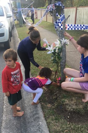 Children from the neighbourhood lay flowers at the edge of the crime scene. 