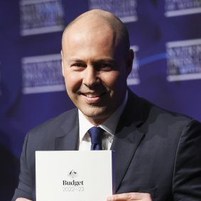 Then-treasurer Josh Frydenberg poses for photos with budget documents in 2022.