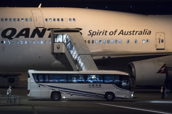 A Japanese worker wearing a protective suit stands next to a bus carrying Australians before boarding the Qantas plane for Darwin. 