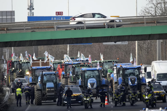 Police forces monitor a farmers demonstration on a highway leading to Paris.