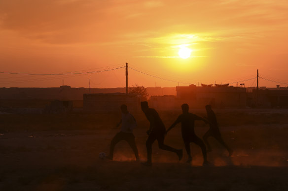 A group of men play football in the yard of a school that has become an unofficial camp for hundreds of Kurds.