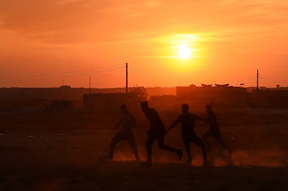 A group of men play football in the yard of a school that has become an unofficial camp for hundreds of Kurds.