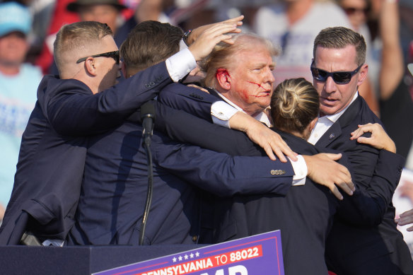 Donald Trump is surrounded by US Secret Service agents following the shooting.