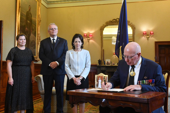 Governor-General David Hurley signs a condolence book as his wife Linda Hurley, Prime Minister Scott Morrison and his wife Jenny Morrison (left) watch on.