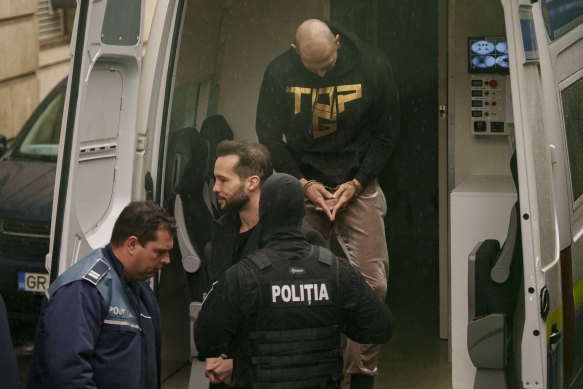 Police officers escort Andrew Tate, centre, handcuffed, next to his brother Tristan to the Court of Appeal in Bucharest, Romania.