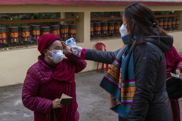 A Tibetan Buddhist nun has her temperature checked at the polliing station in Dharmsala, India on Sunday.