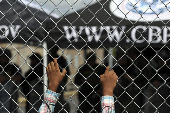 A migrant leans on a fence of the Gateway International Bridge that connects Matamoros in Mexico with Brownsville in Texas in the US.