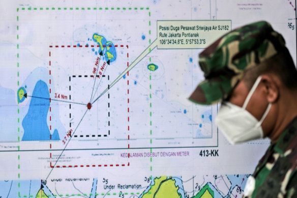 An Indonesian soldier walks past a map showing the location where a Sriwijaya Air passenger jet lost contact with air traffic controllers.