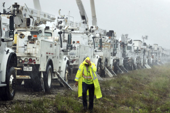 Charles Starling, a lineman with Team Fishel, is pelted with rain as he walks by a row of electrical line trucks stage in a field in The Villages, Florida, in preparation for damage from Hurricane Helene. 