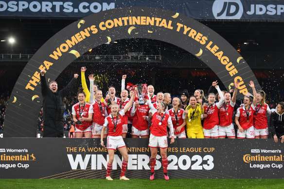 Leah Williamson and Kim Little lift the trophy for Arsenal.