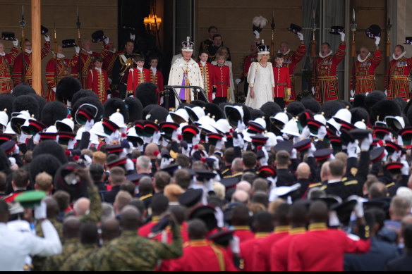 King Charles III and Queen Camilla receive the royal salute from gathered military personnel on the West Terrace of the Buckingham Palace gardens.