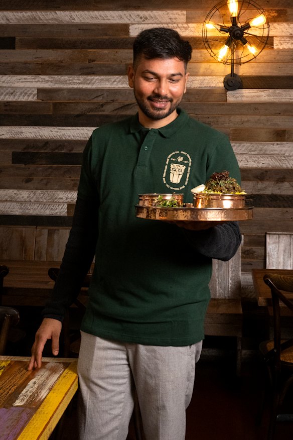Munwar Hussain at his IndoChainese restaurant holding a Gongura chicken biryani.