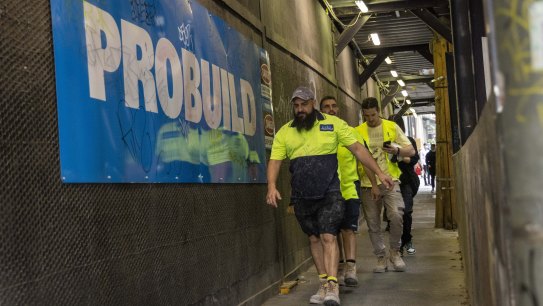 周四早上，工人们在墨尔本中央商务区的 UNO Melbourne 工地收集设备，然后离开。