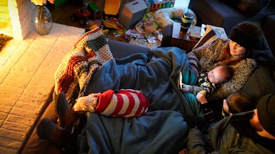 Dan Bryant and his wife Anna huddle by the fire with sons Benny, 3, and Sam, 12 weeks, along with their dog Joey, also wearing two doggie sweaters, with power out and temperatures dropping inside their home after a winter storm brought snow and freezing temperatures to North Texas.