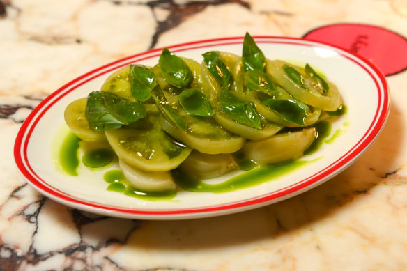 A side dish of soused green tomatoes with basil and olive oil.