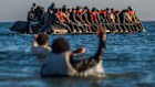 Migrants on the coast of France wade out to a dinghy to cross the English Channel in August.