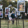 A man walking his dog views photos of people who were killed during Hamas’ attack on the Nova festival at the site.
