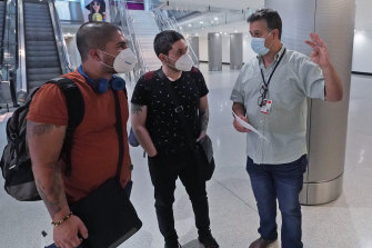 William Gutierrez, right, operations section chief for the Florida Region 7 Incident Management Team, tells arriving passengers Nicolas Pena, left, and his brother Daniel, both from Colombia, about free COVID-19 vaccinations available at Miami International Airport. 
