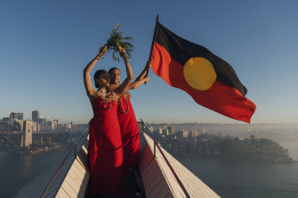 Abigail Delaney and Serene Dharpaloco Yunupingu from the Janawi Dance Clan, from the Darug nation, flying the Aboriginal flag on top of the largest sail of the Sydney Opera House in 2019.