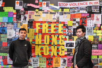 Dennis Chui, left, and Silver Lee stand with the Lennon Wall they helped construct at the University of Technology, Sydney.