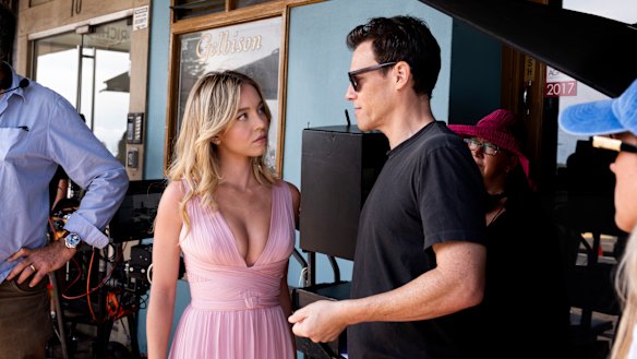Director Will Gluck discusses a shot with Sydney Sweeney at Bondi Beach.