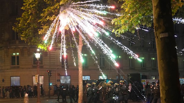 Fireworks explode over riot police officers on the Champs-Elysees avenue after the Champions League final soccer match between Paris Saint-Germain and Inter Milan.
