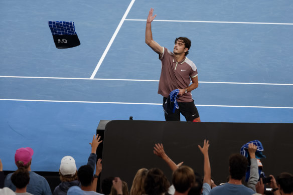 Taylor Fritz throws towels to spectators after beating Stefanos Tsitsipas.