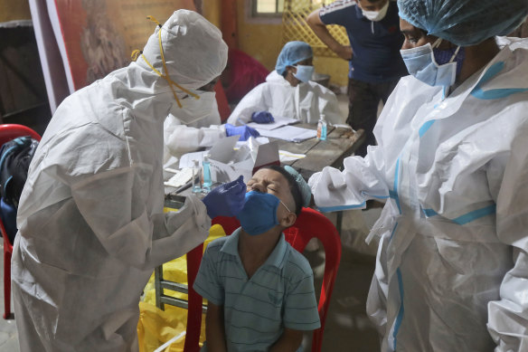 Health workers collect a swab from a boy in Mumbai to test him for COVID-19. 