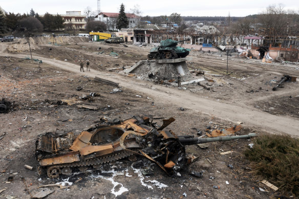Residents pass by a damaged Russian tank in the town of Trostyanets, east of capital Kyiv on Monday. A US official said the town was back under Ukrainian control.