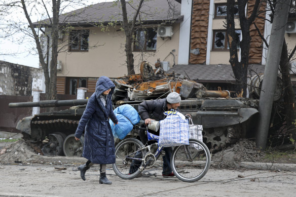Residents walk past a destroyed tank in an area of Mariupol controlled by Russian-backed separatist forces.
