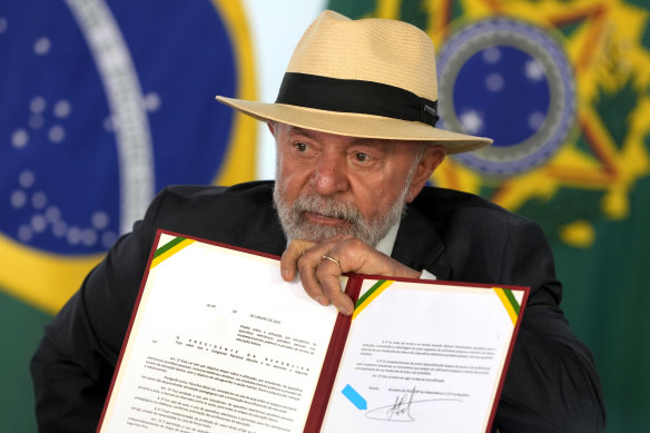 Brazil’s President Luiz Inacio Lula da Silva holds up a bill that restricts the use of mobile phones in schools nationwide, during a ceremony at the Planalto Palace, in Brasilia.