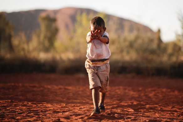 A boy plays while waiting for celebrations marking the closure of the Uluru climb. 