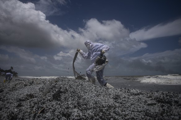 A Sri Lankan navy soldier clad in a protective suit walks on the mounds of debris washed ashore from the burning Singaporean ship on Thursday.