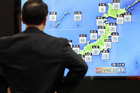 A man watches a TV weather forecast on Friday ahead of the typhoon's expected arrival on Saturday.