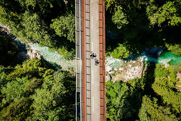 Cyclists pass over a bridge in the mountainous countryside near Tarvisio where the borders of three nations converge.