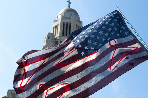 An American flag decorated with coat hangers flies over a crowd of protesters during an Abortion Rights Rally held in front of the Nebraska State Capitol in Lincoln.
