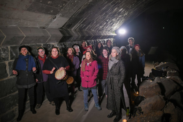 Director Sue Johnson (holding the drum) with her choir, the Trolls, singing under the Murray Road bridge in Coburg.