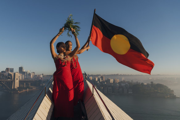 Abigail Delaney and Serene Dharpaloco Yunupingu from the Janawi Dance Clan, from the Darug nation, flying the Aboriginal flag on top of the largest sail of the Sydney Opera House in 2019.