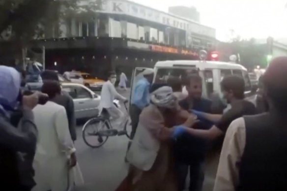 People tend to a wounded person near the site of a deadly explosion outside the airport in Kabul, Afghanistan.