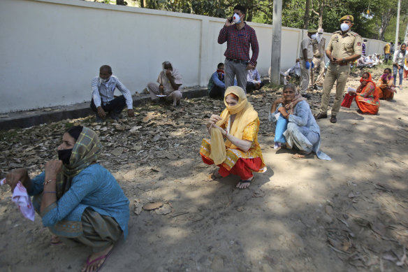People squat as they wait outside a bank to withdraw money during lockdown on the outskirts of Jammu, India.