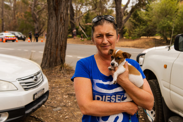 Lorie Kavanagh, with her puppy, Archie, waits at the roadblock on the road into Buxton and other fire-affected communities. 