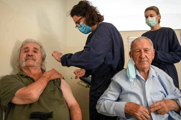 John Manolakakis and his father Jim receive their shots at Altona North Respiratory Clinic on Monday, administered by nurses Peirrene McConville (left) and Chloe Coffin.