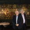 Tolarno Hotel owners Bernard Corser and James Fagan in front of a historic Mirka Mora mural in the hotel’s restaurant.