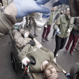 Taira assists as a serviceman is brought in on a stretcher in Mariupol.