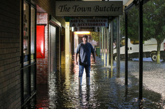 Butcher Chris Krstev looks on as floodwater inundates the shopping strip on Hamilton Street.
